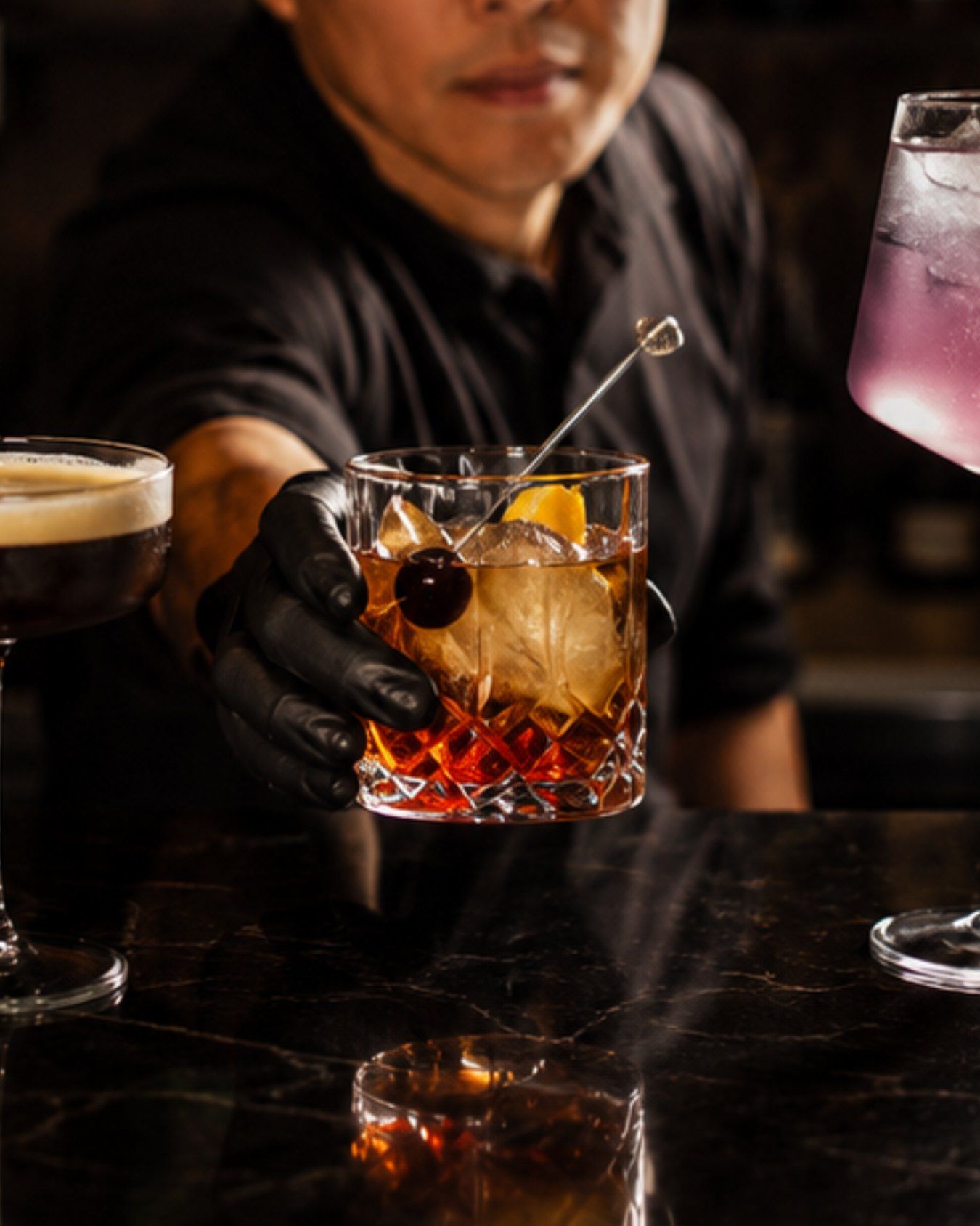 A bartender serving an old fashioned at the bar