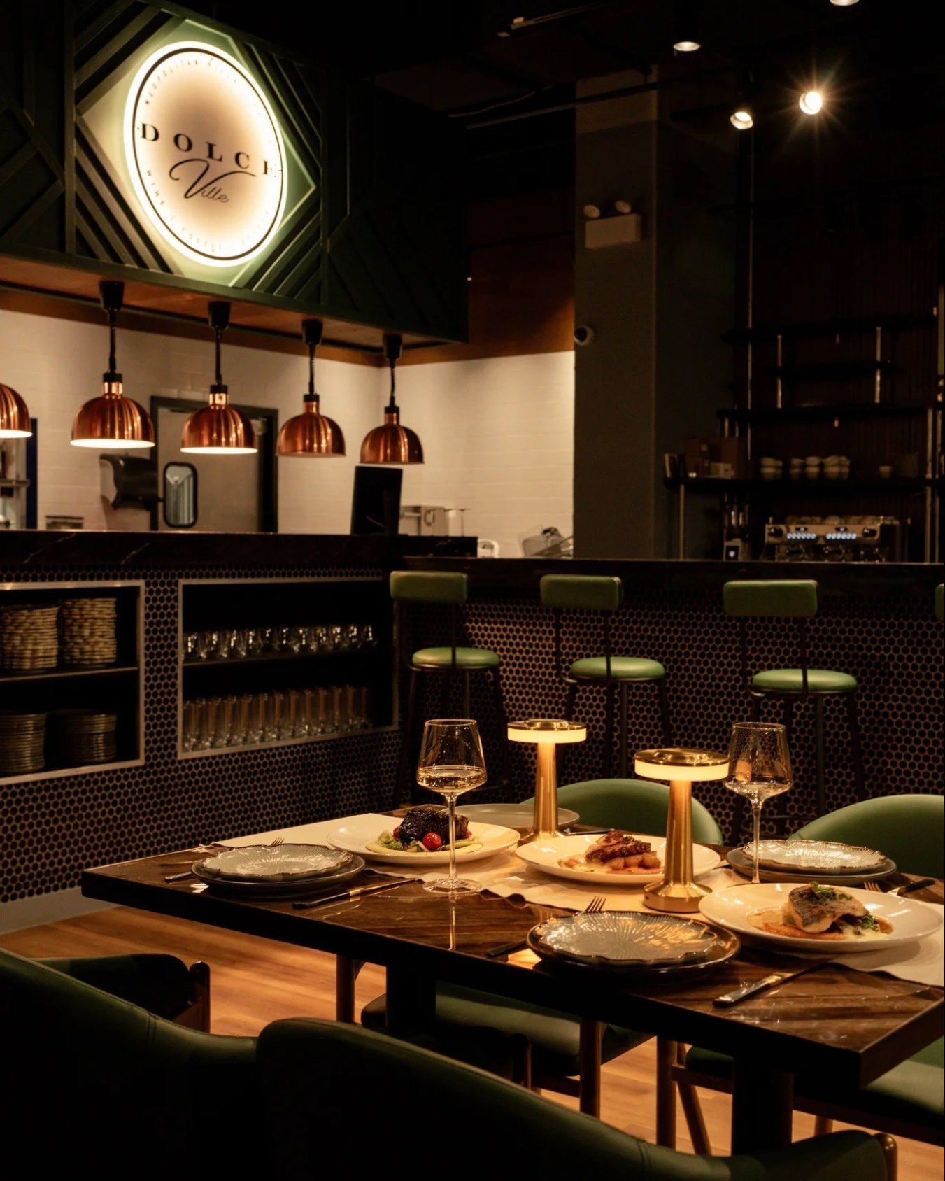 A table set with pizzas and wine under the Dolce Ville sign